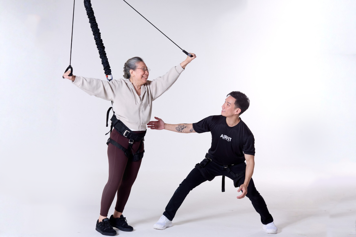 AIRFIT Bungee Fitness Training Session with Instructor Assisting Senior Participant in Safe Suspension Workout