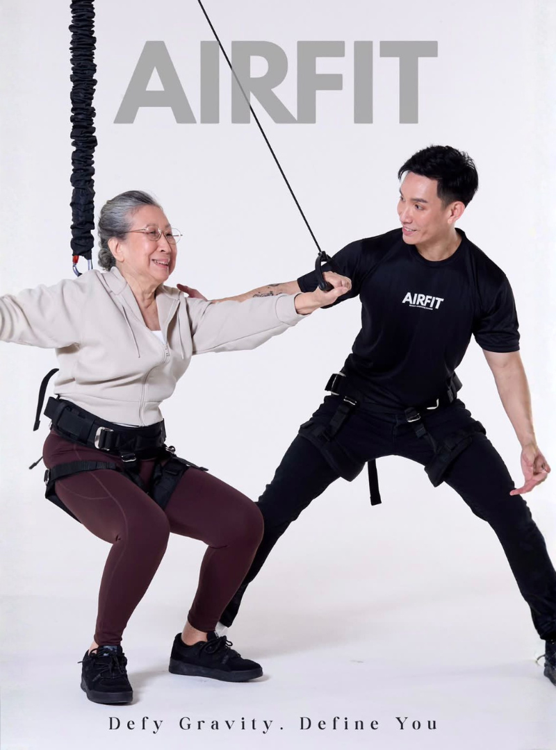 Senior participant performing AIRFIT bungee fitness workout with professional instructor guidance